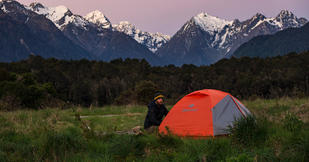 eric using a marmot tent in front of a mountain landscape backpacking and hiking