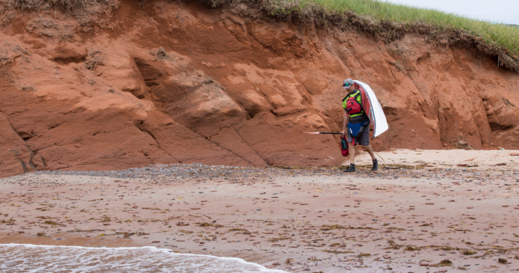 ken whiting carrying a trak 2.0 kayak while Sea Kayaking Îles de la Madeleine, Québec