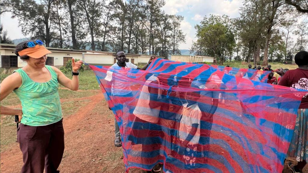 Jessie Stone of Soft Powered Health hanging out with kids showing off a mosquito net: A key element to helping prevent malaria that's rampant in the district.