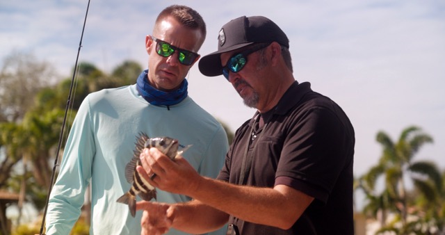 Captain Chris pointing out the sharp barbs on a Convict Fish to Chef Corso