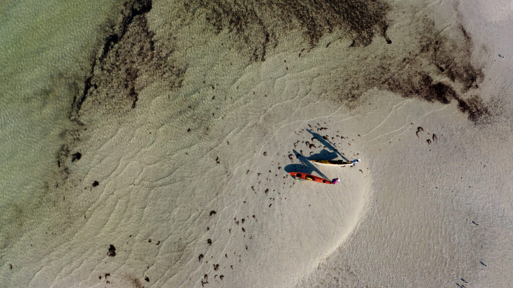 Aerial view of Chef Corso and Guide, Misty Wells pulling their sea kayaks over the sandy shallows.