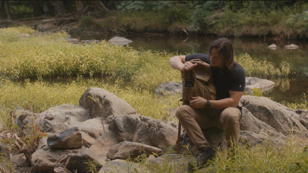mike sitting on rock opening Mystery Ranch Rip Ruck day pack